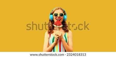 Summer colorful portrait of cheerful happy smiling young woman model posing in headphones listening to music with juicy slice of watermelon on yellow background