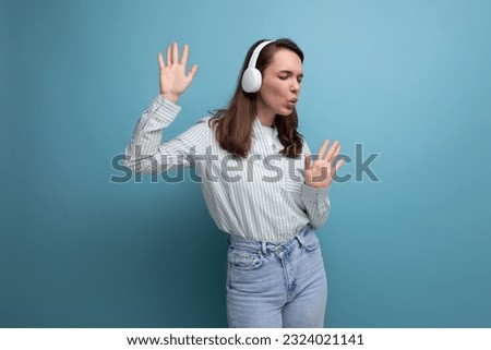 optimist energetic brunette young lady with hair below her shoulders listens to music with headphones