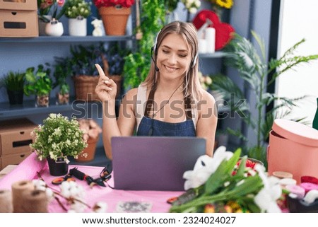Blonde caucasian woman working at florist shop online smiling happy pointing with hand and finger to the side 