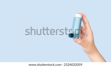 Hands holding asthma inhaler for relief asthma attack isolated blue background. Pharmaceutical products is used to prevent and treat wheezing and shortness of breath caused asthma or COPD. Royalty-Free Stock Photo #2324032059