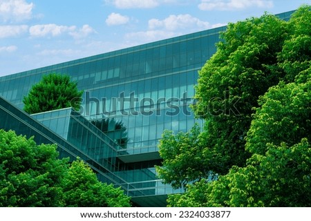 Eco-friendly building in the modern city. Sustainable glass office building with trees for reducing heat and carbon dioxide. Office building with green environment. Corporate building reduce CO2.  Royalty-Free Stock Photo #2324033877