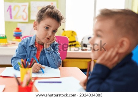 Adorable boys preschool students sitting on table drawing on paper at kindergarten Royalty-Free Stock Photo #2324034383
