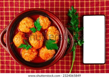 Chicken Meatballs in tomato sauce and smartphone with white blank screen Royalty-Free Stock Photo #2324065849