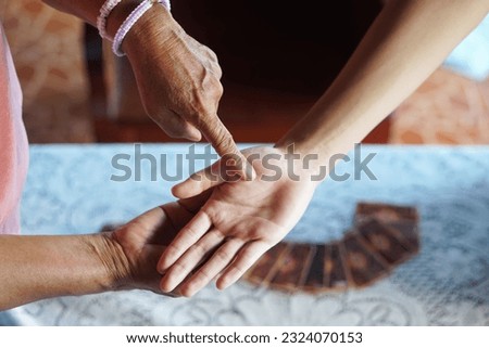 Fortune teller finger points on customer's  palm . Concept , palmistry, astrology. Foretelling, mystery, magic, fortune, fate. Prediction for future life ,events.               Royalty-Free Stock Photo #2324070153