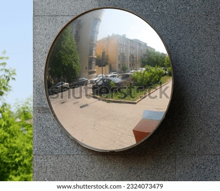 Abstract defocused distorted image of urban landscape. Parked cars. Summer. Reflection in spherical mirror mounted on the wall of house. Concept of road safety. Copy space.
 Royalty-Free Stock Photo #2324073479