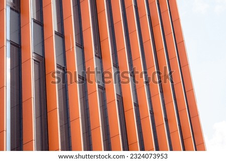 Orange, metal, vertical columns on the facade of the building. Facade element of modern architecture.