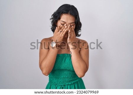 Young hispanic woman standing over isolated background rubbing eyes for fatigue and headache, sleepy and tired expression. vision problem 