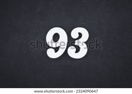 White number 93 on plywood with black paint as background.