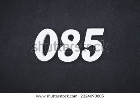 White number 085 on plywood with black paint as background.