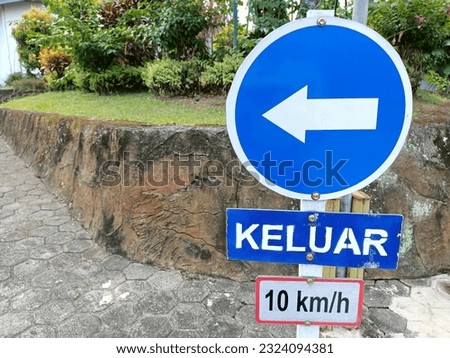 an exit sign in Indonesian language in an alley with a maximum speed of 10 km per hour