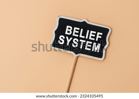 BELIEF SYSTEM - text on a small chalkboard on a beige background. Top view. Business, tips and tricks concept