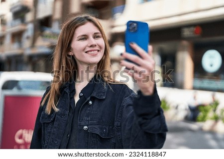 Young blonde woman smiling confident making selfie by the smartphone at street