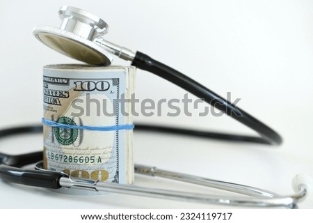 Stethoscope laying on roll of money - Medical costs, doctor's bills, cost of insurance Royalty-Free Stock Photo #2324119717