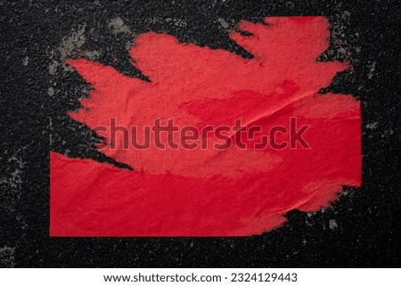 A piece of red paper on a black wall. Royalty-Free Stock Photo #2324129443