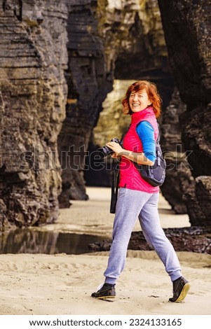 Tourist woman taking travel photo from cliff formations on Cathedral Beach in Galicia Spain. Playa de las Catedrales, As Catedrais in Ribadeo, province of Lugo, northern Spain.