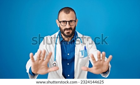 Young hispanic man doctor doing calm gesture with hands over isolated blue background