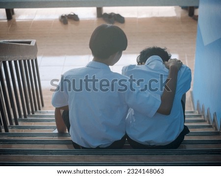 Two students sit down and hug to support a depressed man - a man supports his friend in despair for his love problems. The concept of best friends Royalty-Free Stock Photo #2324148063