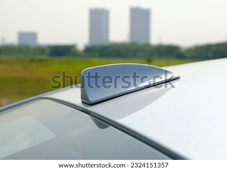 Selective focus picture of shark fin radio antenna on car roof.