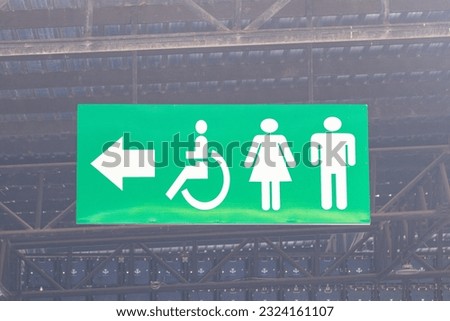 Signs Modern public toilet or bathroom sign green on wall hanging from ceiling of men, women, people with disabilities with person icon. Symbol notifying people to use service in restaurants, parks. 