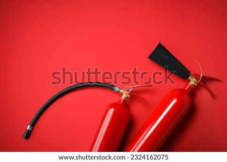 Fire extinguishers on red background, flat lay. Space for text