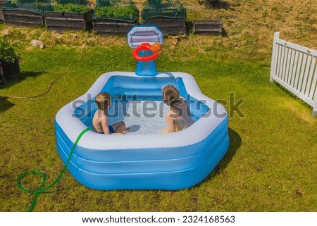 Beautiful view of two boys in inflatable outdoor swimming pool playing water basketball on sunny summer day. Sweden.