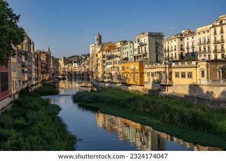 Girona, city of Spain with the Ter, Güell, Galligans and Oñar rivers and one of the bridges. Background reflected in the river, water. Old colored houses in line, daytime architecture with sunlight