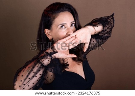 Coaching woman making hand gestures near her mouth. Surprise and stress sign. Motivational management. Isolated on brown background.