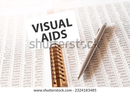 Text VISUAL AIDS on paper card, pen, financial documentation on table - business, banking, finance and investment concept. close up of stock market chart.