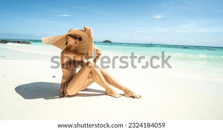 Woman on tropical vacation relaxing  on the sandy beach with turquoise water, wearing bikini and summer hat. Paradise in Thailand. Asia. Traveler. Wanderlust.
