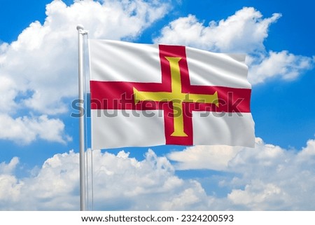 Guernsey national flag waving in the wind on clouds sky. High quality fabric. International relations concept