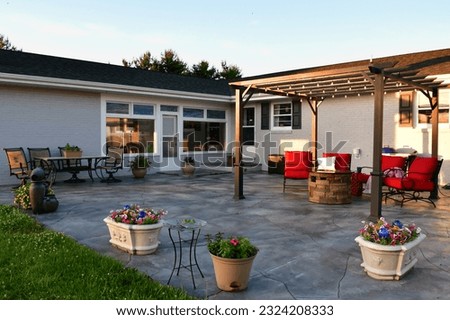 Patio living space with comfortable seating around fire pit under pergola Royalty-Free Stock Photo #2324208333