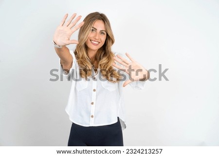 Young caucasian business woman wearing white shirt over white background  showing and pointing up with fingers number ten while smiling confident and happy.