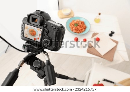 Professional camera with picture of spaghetti on display in studio, space for text. Food stylist