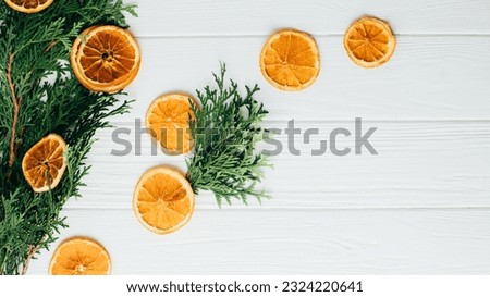 White textured wooden background with green thuja branch and dry orange slices. Background of light wooden boards for design, web banner