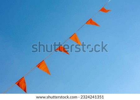 Selective focus of pennant orange flags waving in the air with blue clear sky as background, Orange colour fever is a phenomenon in the Netherlands that occurs during major events in Dutch culture. Royalty-Free Stock Photo #2324241351