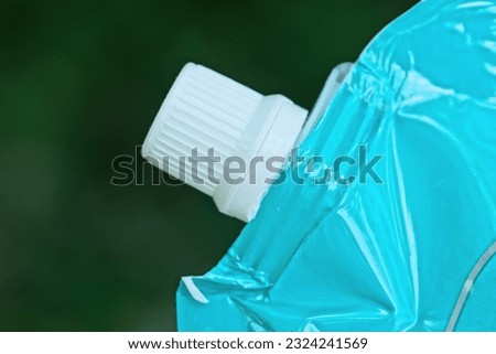 part of one blue plastic bag closed with a white lid on a green background