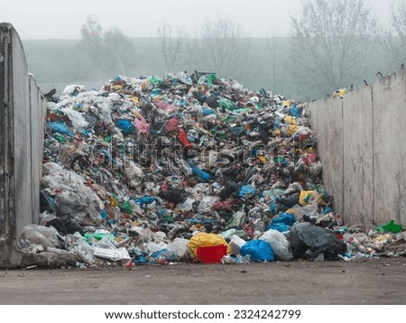 Landfill site, a pile of stinky different junk disposal in the concrete section for unsorted waste materials Royalty-Free Stock Photo #2324242799