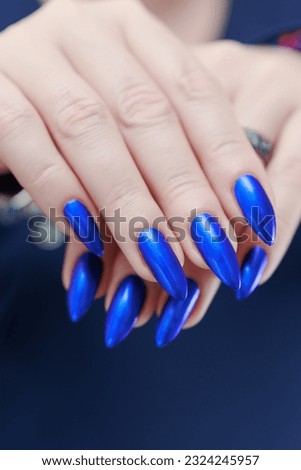 Woman's beautiful hand with long nails and bright blue manicure
