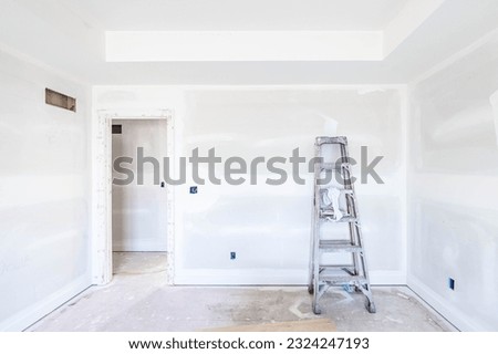 High and dirt ladder put by unfinished drywall on the floor in empty room at construction site. New build property project. Home improvement, house renovation concept. Ready for Interior and paintwork Royalty-Free Stock Photo #2324247193