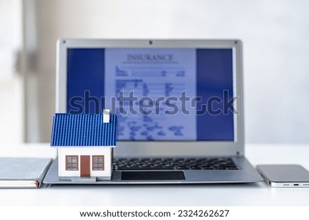 Small house on table with laptop as background, insurance concept and home purchase