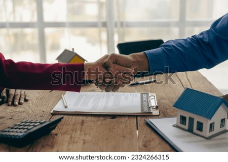 Real estate agent and client celebrating contract completion after signing at table in office