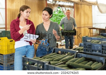Women with documents are discussing at the boxes with cucumbers