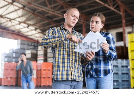 Man and woman workers with papers working at the storehouse Royalty-Free Stock Photo #2324274573