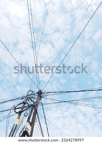 Electricity and telephone poles with messy lines, against the background of a bright blue sky in the morning in a residential area in Tangerang, Indonesia