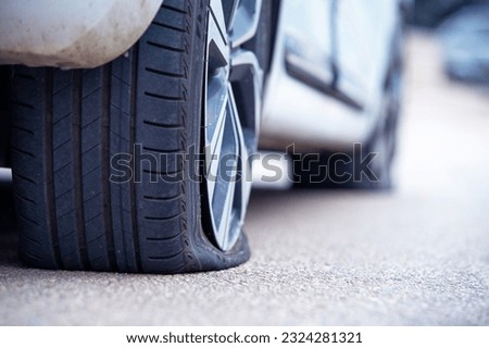 Rear right flat tire of car close-up. Insured event machine accident, tire puncture. Vehicle stands on the road with perforated rubber on a wheel with a metal disc. ServiceMobile tire fitting. Royalty-Free Stock Photo #2324281321