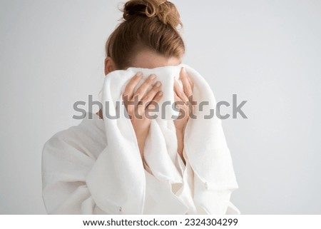 The girl wipes her face with a terry towel. Royalty-Free Stock Photo #2324304299