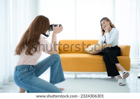 Beautiful asian woman photographer taking picture with professional camera at home