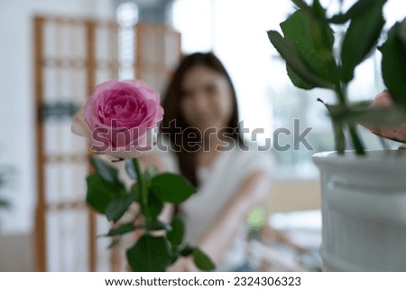 Beautiful young asian woman florist cutting rose flower in flower shop