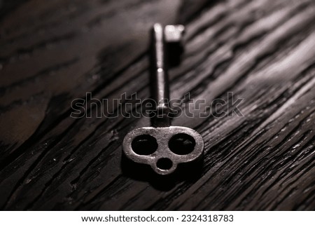 An vintage key on an grungy old desk with a beam of light coming.