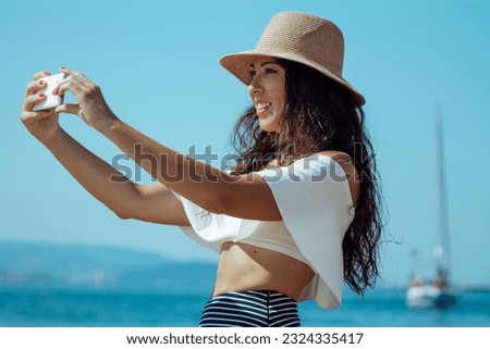 young woman on the beach making a selfie or live video with the mobile phone